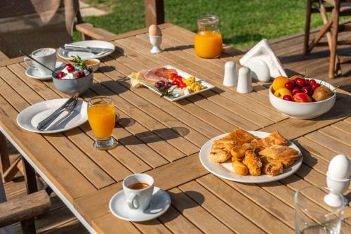 a wooden table topped with plates of food and orange juice at Harmony Hotel in Kourouta