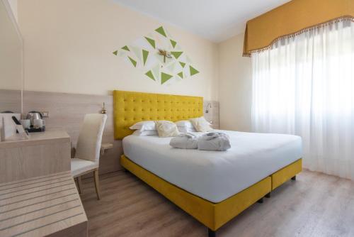 a bedroom with a large bed with a yellow headboard at Hotel Castello Artemide Congressi in Castel San Pietro Terme