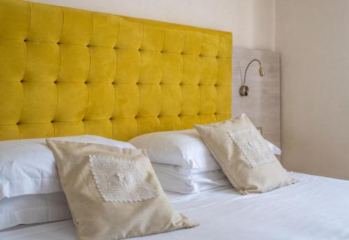 a bed with a yellow headboard and two pillows at Hotel Castello Artemide Congressi in Castel San Pietro Terme
