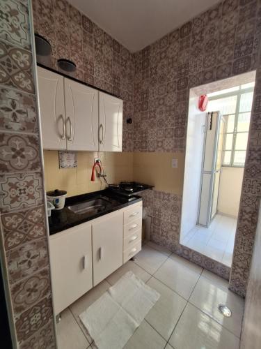 a kitchen with white cabinets and a sink and a window at Loft in the Center of Serra Negra in Serra Negra