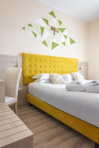 a bedroom with a large bed with a yellow headboard at Hotel Castello Artemide Congressi in Castel San Pietro Terme