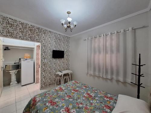 a bedroom with a bed and a television and a refrigerator at Loft in the Center of Serra Negra in Serra Negra