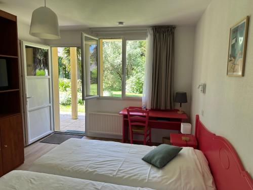 a bedroom with a bed and a desk and a window at Logis Hôtel La Demeure du Perron in Quettehou