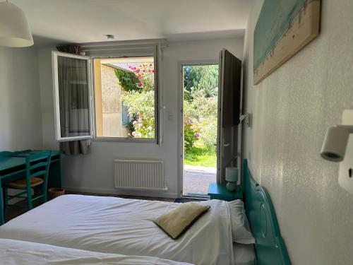 a bedroom with a bed and a window at Logis Hôtel La Demeure du Perron in Quettehou