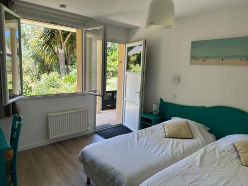 a bedroom with a bed and a large window at Logis Hôtel La Demeure du Perron in Quettehou