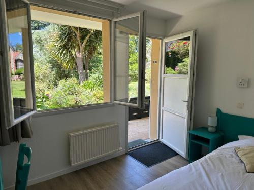 a bedroom with a bed and two large windows at Logis Hôtel La Demeure du Perron in Quettehou