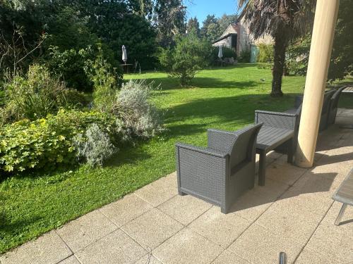 two chairs sitting on a patio in a garden at Logis Hôtel La Demeure du Perron in Quettehou