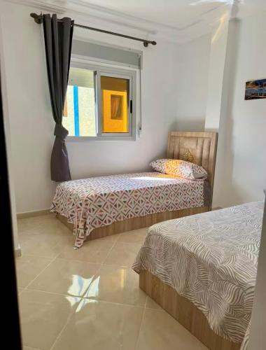 a bedroom with two beds and a window at Appartement Neuf Plage Mdiq in M'diq