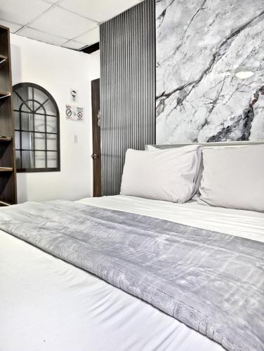 a bedroom with a white bed with a marble wall at Hostal Yoha in Panama City