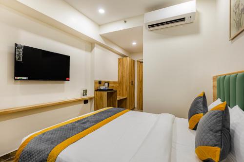a bedroom with a bed and a tv on the wall at MONDAY PREMIUM Madhapur in Hyderabad