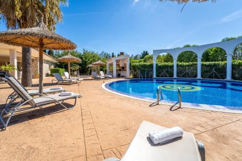 a resort pool with chairs and an umbrella at Ideal Property Mallorca - Son Manyo 223 in Sa Pobla