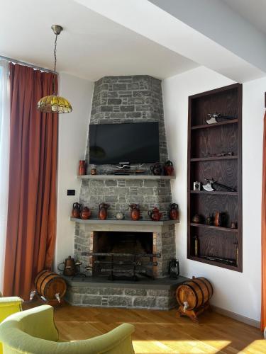 a living room with a fireplace with a flat screen tv at Hotel Kanione in Çorovodë