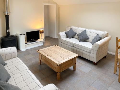 a living room with a couch and a coffee table at Little Barn - Hw7615 in Bettws-yn-Rhôs