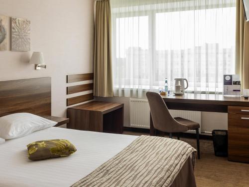 a hotel room with a bed and a desk at Mercure Marijampole in Marijampolė