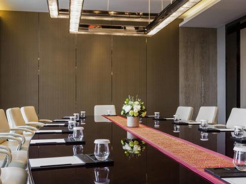 a conference room with long tables and white chairs at Pullman Weifang in Weifang