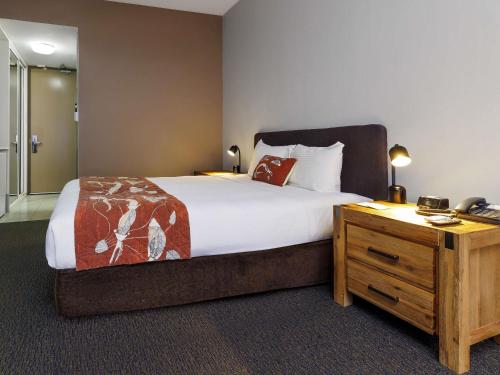 a bedroom with a large bed and a wooden dresser at Mercure Kakadu Crocodile in Jabiru