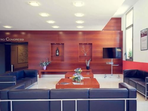 a lobby with couches and a table and a tv at Mercure Genova San Biagio in Genova