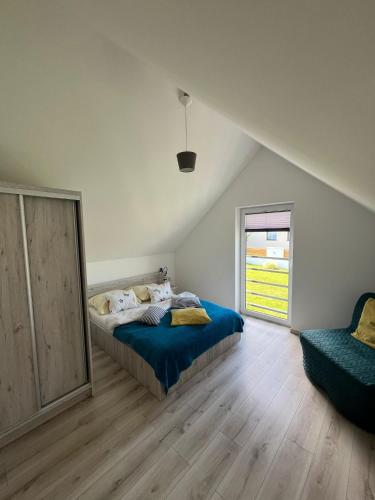 a bedroom with a bed and a window and a chair at Domki Ancora - komfortowe domki nad morzem in Jastrzębia Góra