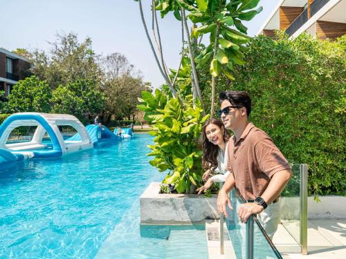 a man and a woman sitting next to a swimming pool at SO/ Sofitel Hua Hin in Cha Am