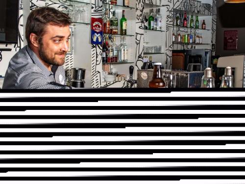a man sitting at a bar behind a counter at Ibis Sofia Airport Hotel in Sofia