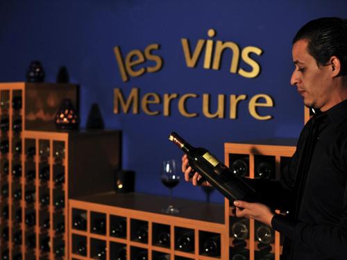 a man is holding a bottle of wine at Mercure Quemado Al-Hoceima Resort in Al Hoceïma