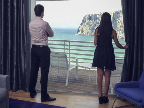 a man and woman looking out a window at the ocean at Mercure Quemado Al-Hoceima Resort in Al Hoceïma