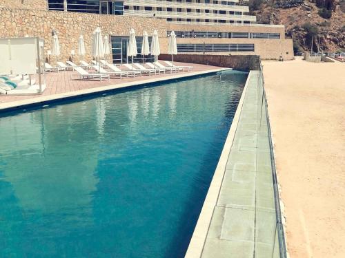 a pool of blue water next to a beach at Mercure Quemado Al-Hoceima Resort in Al Hoceïma