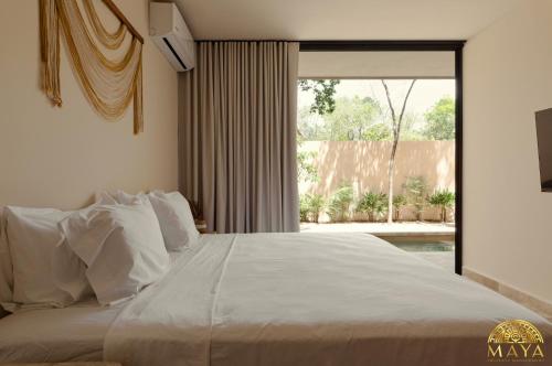 a bedroom with a white bed with a large window at Peregrina Tulum Lux Aparthotel in Tulum