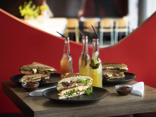 a table with three sandwiches and bottles of sauce at ibis Londrina Shopping in Londrina