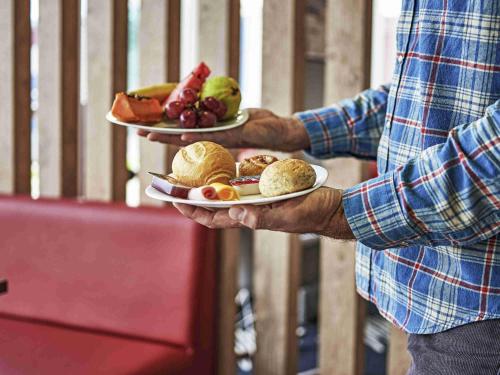 a man is holding two plates of food at ibis Londrina Shopping in Londrina