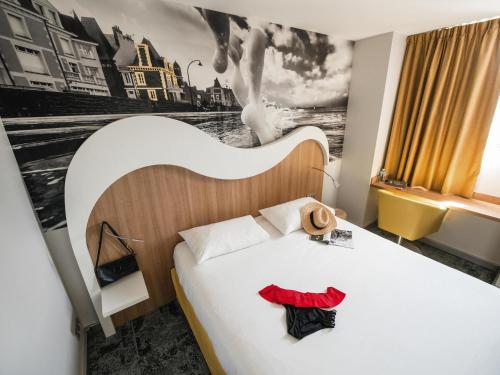 a bedroom with a white bed with a black and white picture at ibis Styles Saint Malo Port in Saint Malo