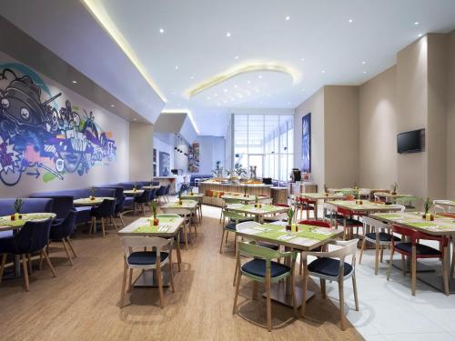 a restaurant with tables and chairs and a mural at Ibis Styles Jakarta Mangga Dua Square in Jakarta