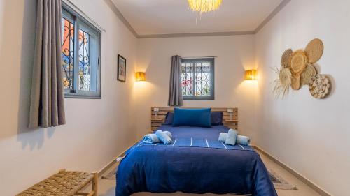 a bedroom with a blue bed and a window at Riad Ghazal in Essaouira