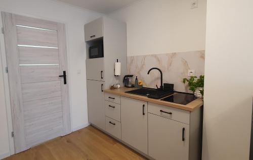 a kitchen with white cabinets and a sink and a door at VESTA Apartamenty M52 Free parking in Szczecin