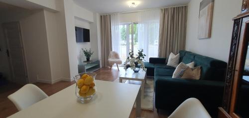 a living room with a white table and a blue couch at VESTA Apartamenty M52 Free parking in Szczecin