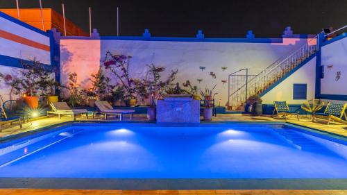 a swimming pool at night with a mural on the wall at Riad Ghazal in Essaouira
