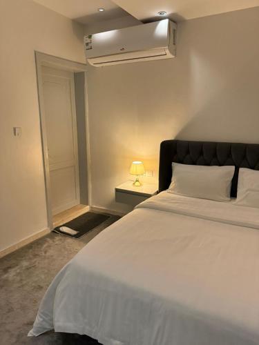 a bedroom with a large white bed and a lamp at Cozy Studio in Jeddah