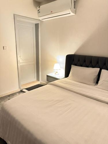 a bedroom with a white bed with a black headboard at Cozy Studio in Jeddah