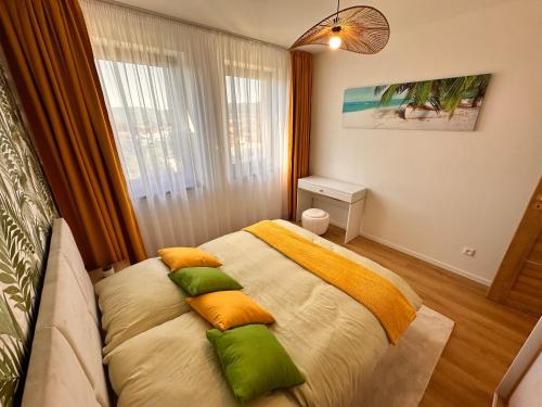 プレショフにあるA&M Apartments - brand new luxury & business apartment Solny Potokのベッドルーム1室(黄色と緑の枕が付いたベッド1台付)