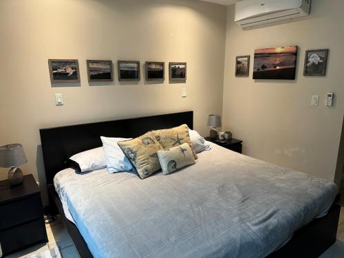 a bedroom with a bed with pillows and pictures on the wall at Beachside 1st Floor Condo Near Flamingo & Conchal in Playa Flamingo