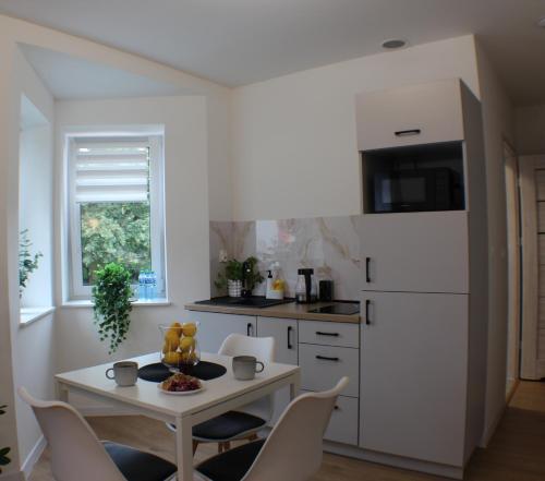 a white kitchen with a table and chairs at VESTA Apartamenty M52 Free parking in Szczecin