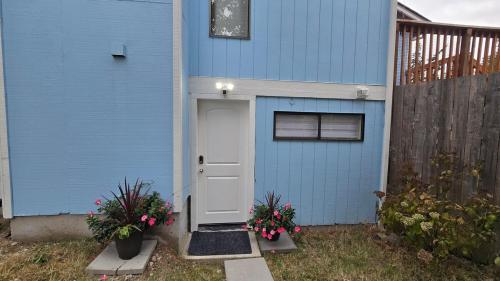 Una casa azul con una puerta blanca y algunas flores. en Guest apartments The Comfy Nest, en Federal Way