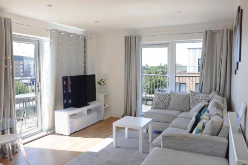 a living room with a couch and a tv at Top-Floor Penthouse with Panoramic Views in Romford