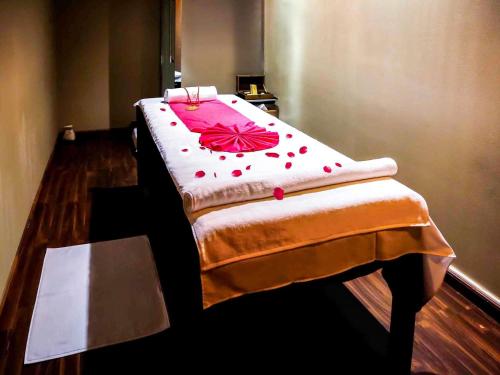 a bed with a red flower on it in a room at Grand Mercure Majlis Residences Abu Dhabi in Abu Dhabi