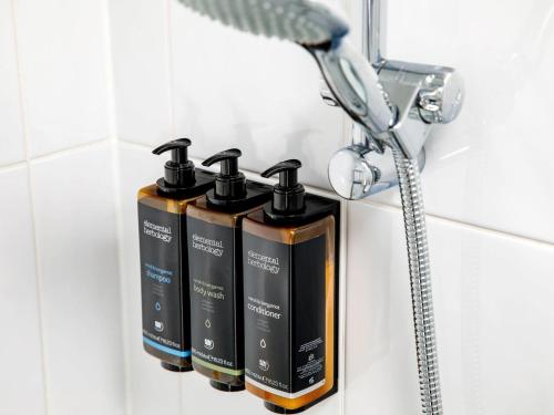 a row of four shampoo bottles on a shelf in a bathroom at Mercure Sheffield Parkway in Sheffield