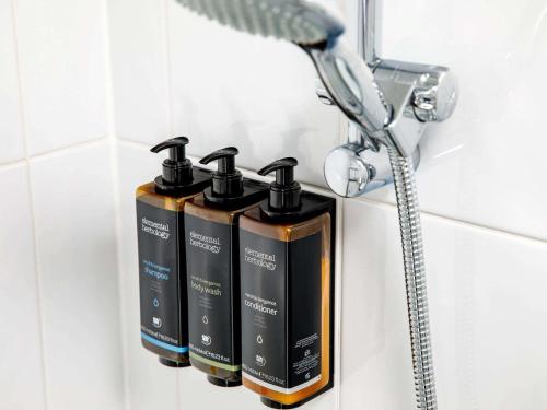 a row of four shampoo bottles on a rack in a bathroom at Mercure Sheffield Parkway in Sheffield