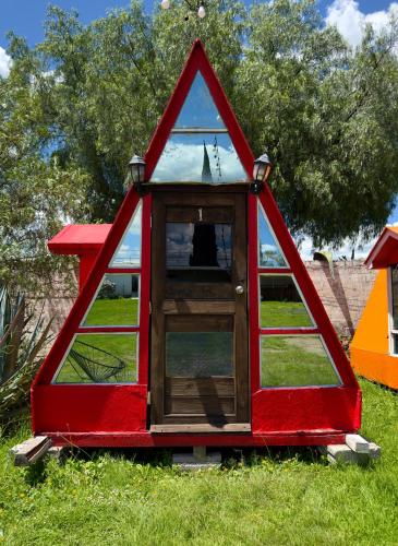 a red play house with a window in the grass at Vicalis Hotel, Villas y Glamping in San Sebastian Xolalpa