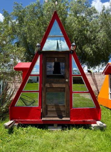 a red play house with a window in the grass at Vicalis Hotel, Villas y Glamping in San Sebastian Xolalpa