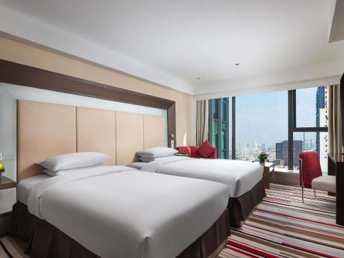 a hotel room with three beds and a large window at Novotel Nanjing Central in Nanjing