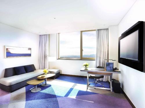 a living room with a couch and a flat screen tv at Novotel Ambassador Suwon in Suwon